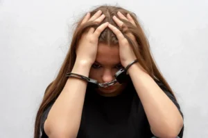 A young woman sits in handcuffs