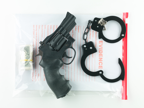 Gun, handcuffs, and evidence bag symbolizing firearm charges handled by a Waco gun crimes lawyer.