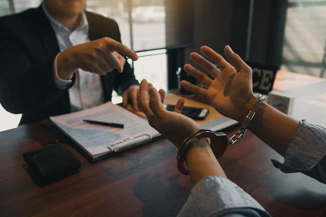 Criminal defense attorney consulting with a handcuffed client facing federal gun charges and illegal weapons possession allegations.