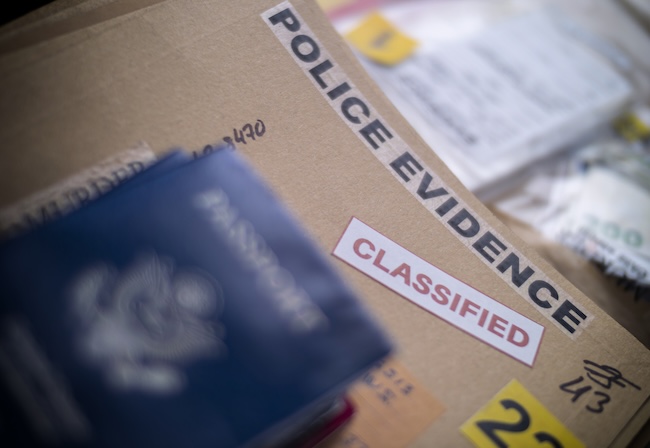 Detective reviewing criminal investigation evidence and case files on desk representing warning signs someone is being investigated for a crime