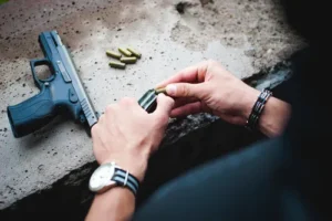 A person loading a handgun, symbolizing the seriousness of federal firearms offenses and the importance of hiring an experienced gun charge lawyer in Texas.