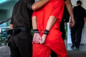 Man in handcuffs being led into court facing serious criminal charges defended by a human trafficking defense lawyer.