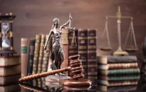 Desk with law books - justice statue - scales - and gavel symbolizing the work of a juvenile criminal attorney.