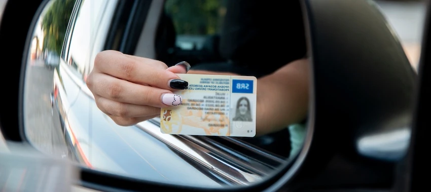 A woman with painted nails holds her driver's license out of a car window for a DWI arrest in Texas.