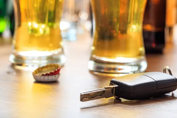 Car keys on a table next to beer